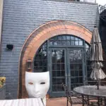 Slate-sided patio featuring a copper-arched doorway and a large white face sculpture.