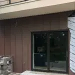 Brown standing seam metal siding around a sliding glass door.