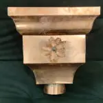 Decorative copper gutter conductor head with an embossed flower.