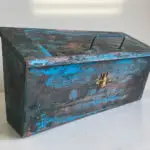 Weathered blue and copper metal box with a decorative gold bee.