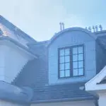 Arched metal dormer window on a gray slate roof.