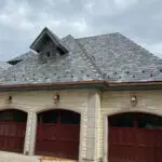 Stone garage with slate roof, copper gutters, and three arched doors.