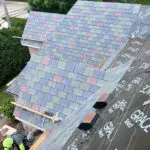 An aerial view of workers installing multicolored slate shingles over Grace Select underlayment.
