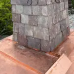 Copper chimney flashing installed around a slate tile chimney.
