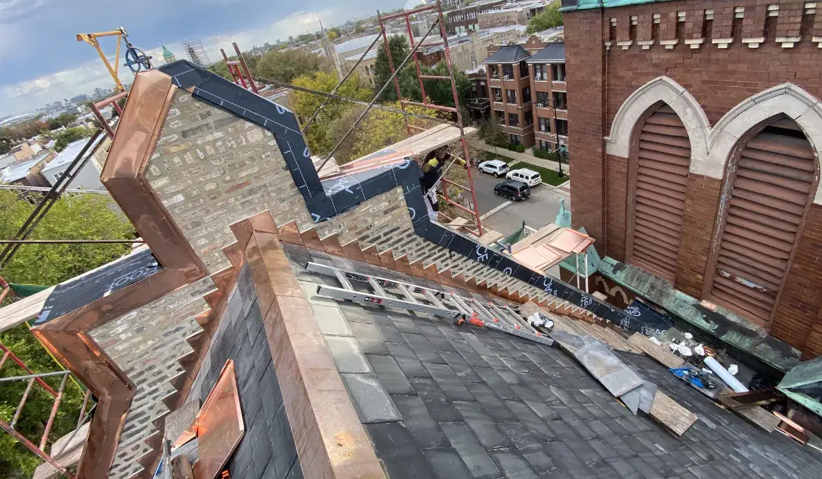 Aerial view of copper roof work underway on a large brick mixed-use building