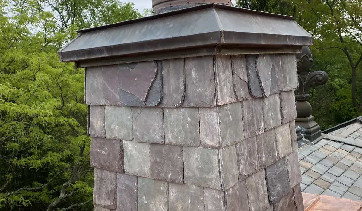 Slate-clad chimney rebuilt with a new copper cap and base flashing — repair rather than replacement